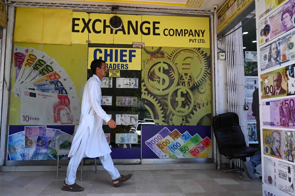 A man walks past foreign currency exchange market in Islamabad on July 11, 2023. (Photo by Aamir Qureshi / AFP)
