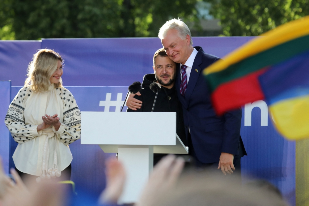 Ukrainian President Volodymyr Zelensky (centre) gets a hug by Lithuania's President Gitanas Nauseda after addressing the crowd at Lukiskiu Square in Vilnius on July 11, 2023, during a NATO Summit. (Photo by Petras Malukas / AFP)

