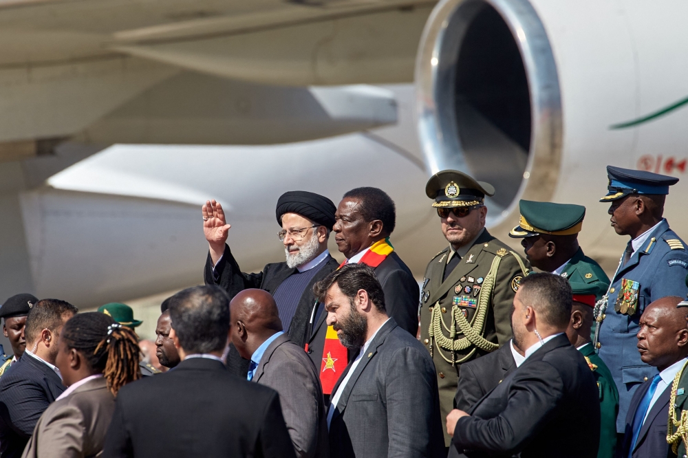 Zimbabwe President Emmerson Mnangagwa (C-R) looks on as he welcomes Iranian President Ebrahim Raisi (C-L) who arrived on a state visit at the Robert Gabriel Mugabe International Airport in Harare on July 13, 2023. (Photo by Jekesai NJIKIZANA / AFP)
