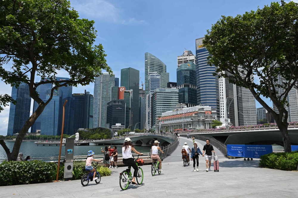In this file photo taken on April 24, 2023 people walk across Jubilee Bridge at Marina Bay in Singapore. Photo by Roslan RAHMAN / AFP

