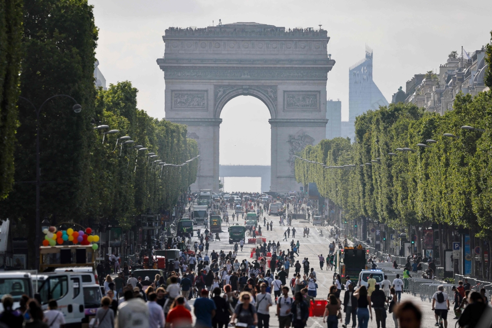 Pedestrians walk on Champs-Elysees avenue in Paris, on July 2, 2023, a day after protesters took to the street and clashed with police on an iconic street popular with tourists during a protest against the police killing of a 17-year-old teenage boy. (Photo by Ludovic MARIN / AFP)
