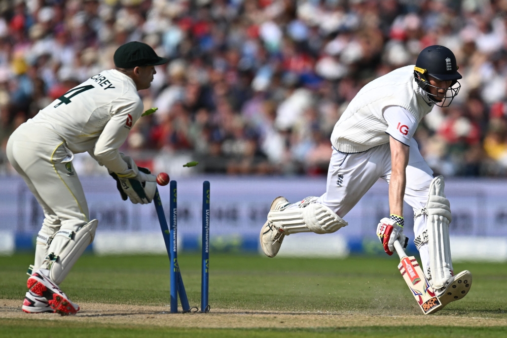 Australia's wicket keeper Alex Carey (L) breaks the stumps but England's Zak Crawley (R) has safely made his ground on day two of the fourth Ashes cricket Test match between England and Australia at Old Trafford cricket ground in Manchester, north-west England on July 20, 2023. (Photo by Oli SCARFF / AFP) 