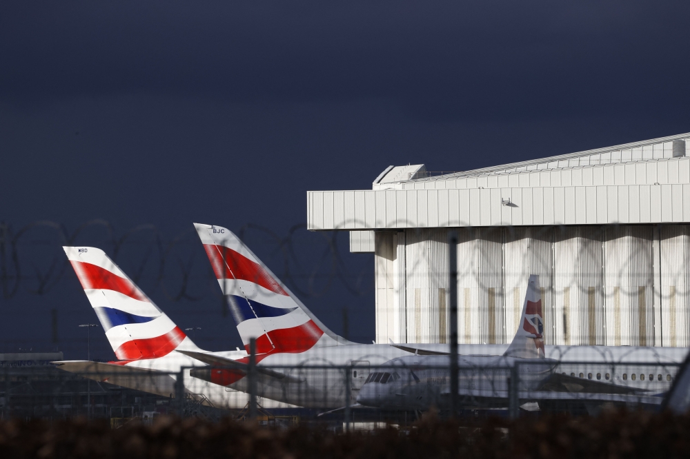 Sunlight illuminates the tailfins of British Airways aircraft at Terminal 5 of London Heathrow Airport in west London (Photo by Adrian DENNIS / AFP)