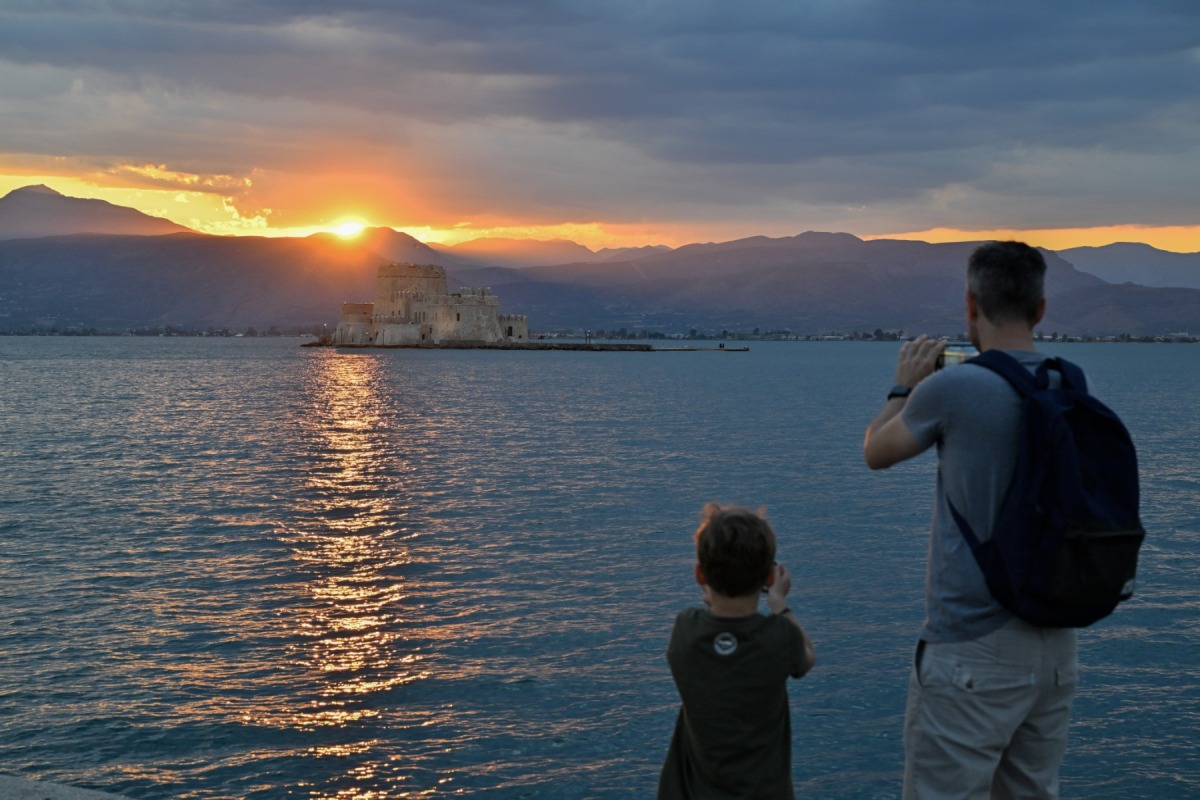 Tourists take photographs during sunset in the city of Nafplion, southern Greece, on July 31, 2023. Photo by Louisa GOULIAMAKI / AFP