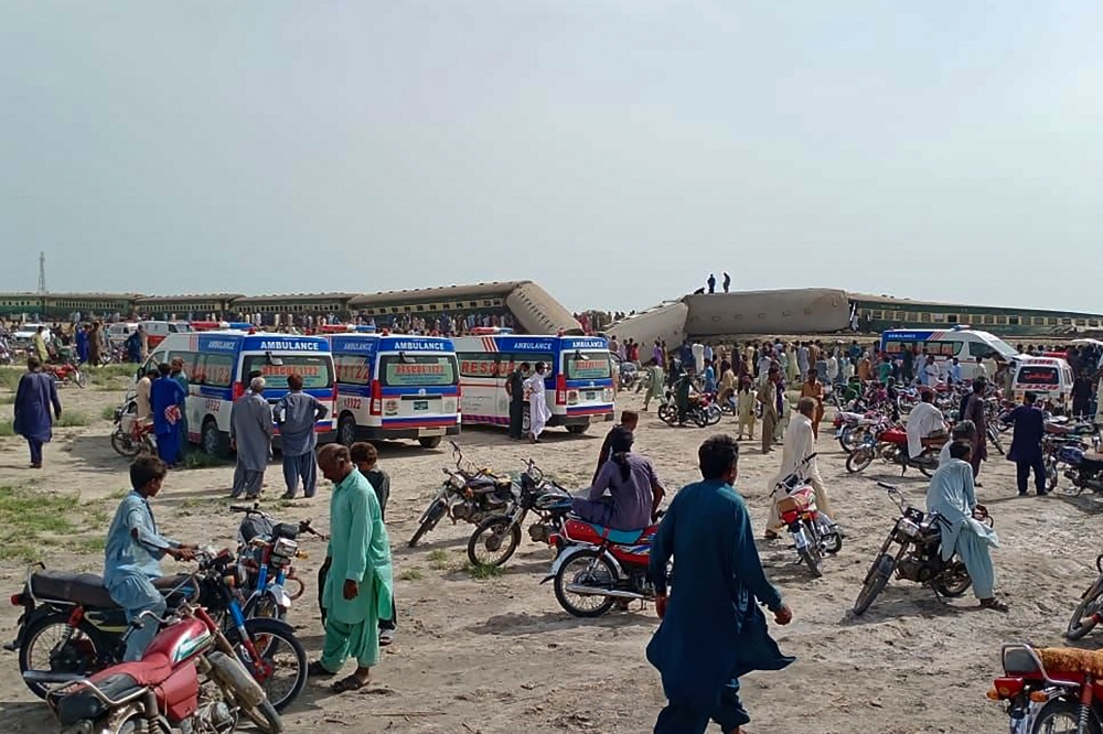 Local residents and ambulances are seen beside carriages following the derailment of a passenger train in Nawabshah, in the Pakistan's southern Sindh province on August 6, 2023. (Photo by AFP)