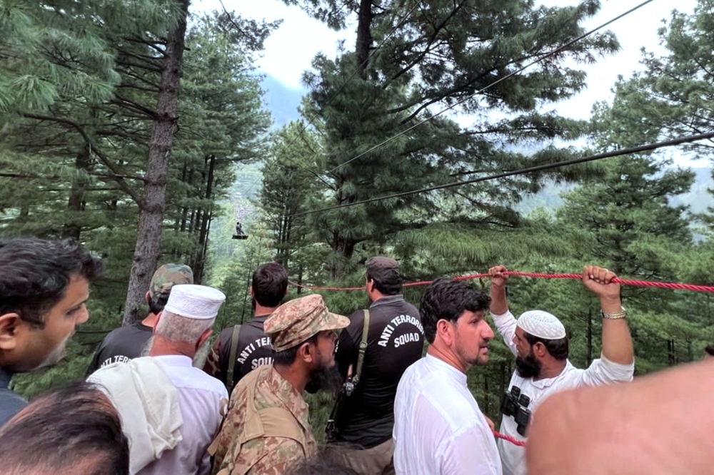 This handout photograph taken on August 22, 2023 and released by the Pakistan's Inter Service Public Relation (ISPR) shows an army soldier (top) rescuing a student survivor, who was trapped in a cable car following an incident, in Pashto village, northwestern Pakistan. (Photo by Handout / ISPR / AFP) 