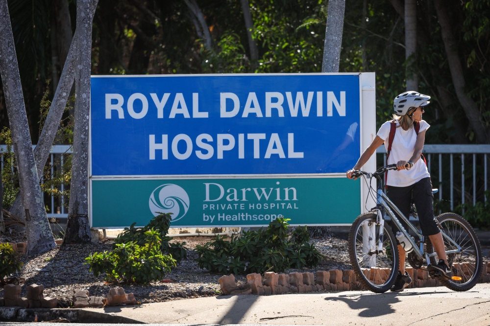A woman rides a bicycle near the entrance to Royal Darwin Hospital in Darwin on August 28, 2023, as investigations continue after three US Marines died on August 27 when an Osprey aircraft crashed on Melville Island, located north of Darwin. (Photo by DAVID GRAY / AFP)