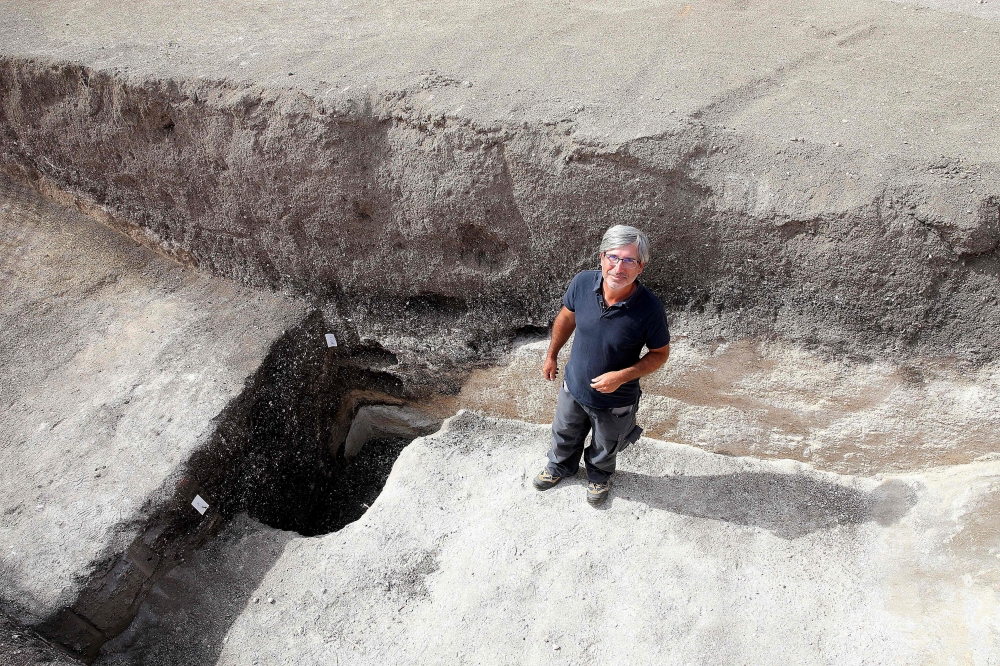 Remi Martineau, researcher at the CNRS, stands at the mouth of a well, dating from the Modern Neolithic, around 3500-years-ago, from a settlement suggesting the presence of a village occupied by a structured population, at Val-des-Marais in the south of the Marne, on August 23, 2023. (Photo by Francois Nascimbeni / AFP)
 