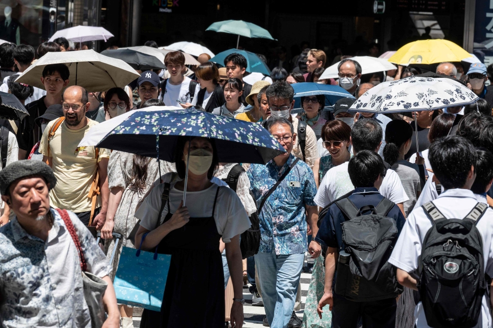 This photo taken on July 30, 2023 shows people using umbrellas and parasols to seek relief from the heat while walking outside Shinjuku station, as temperatures of 35C-plus (95F) have scorched the Japanese capital Tokyo for weeks. Photo by Richard A. Brooks / AFP