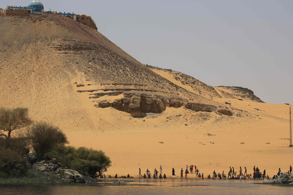 Sudanese who fled the war in their country cool off on the banks of the Nile river in the Egyptian city of Aswan, on September 8, 2023. (Photo by Aahraf Shazly / AFP)

