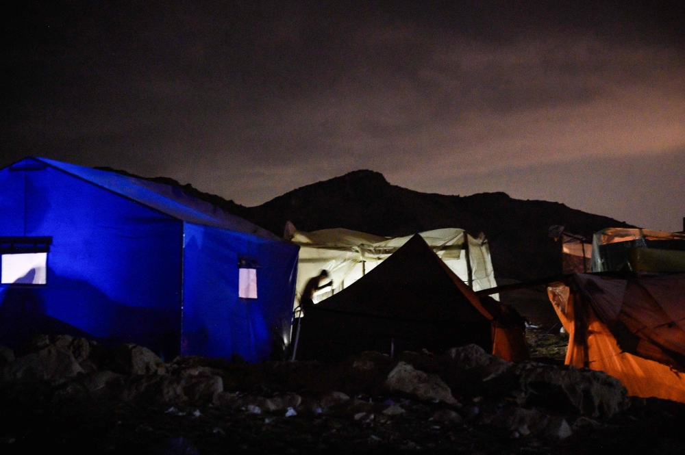 An earthquake survivor gets ready to spend the night in a tent in the village of Moulay Brahim in the central province of Al-Haouz, late on September 14, 2023. (Photo by Philippe Lopez / AFP)
