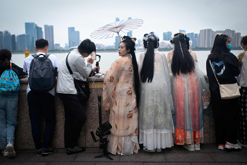 People gather to watch the light show from the Hangzhou Olympic Sports Centre Stadium on the promenade of Qiantang River before the opening ceremony of the 2022 Asian Games in Hangzhou in China's eastern Zhejiang province on September 23, 2023. (Photo by WANG Zhao / AFP)