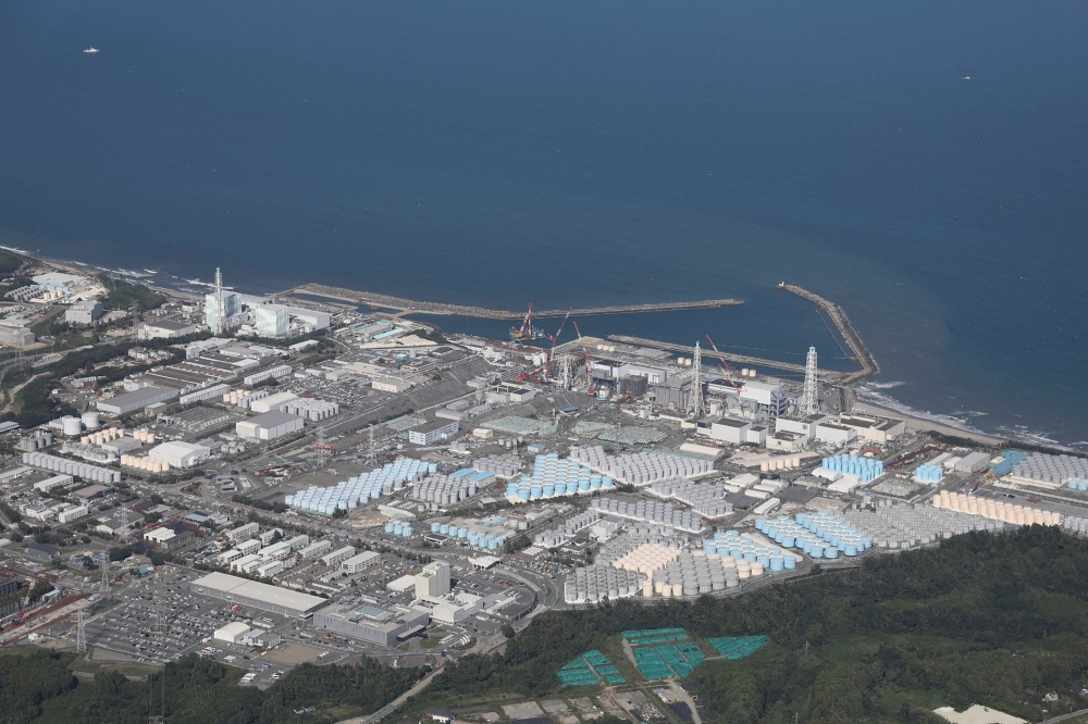 This aerial picture shows storage tanks (bottom) used for storing treated water at TEPCO's crippled Fukushima Daiichi Nuclear Power Plant in Okuma, Fukushima prefecture on August 24, 2023. (Photo by JIJI PRESS / AFP)

