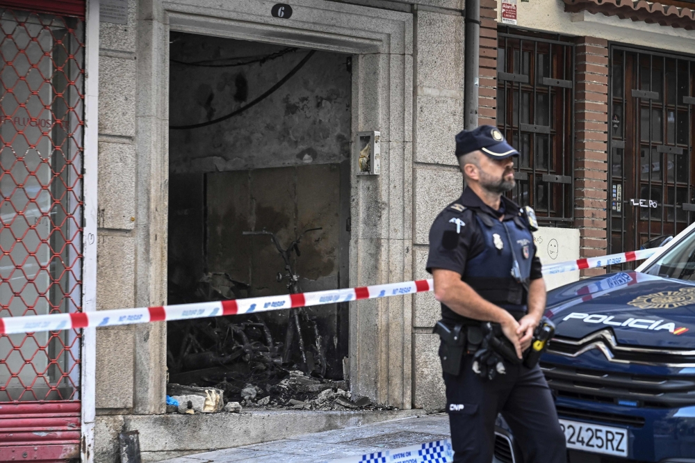 A police officer stands guard next to a building where four minors were killed in a fire in Vigo on October 11, 2023. Photo by MIGUEL RIOPA / AFP