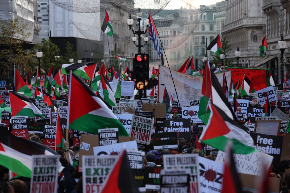 People holding placards and flags of Palestine take part in a 'March For Palestine', part of a pro-Palestinian national demonstration, in London on October 14, 2023. (Photo by Adrian Dennis / AFP)
