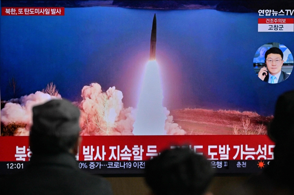File Photo: People watch a television showing a news broadcast with file footage of a North Korean missile test, at a railway station in Seoul on March 19, 2023. (Photo by Anthony Wallace / AFP)