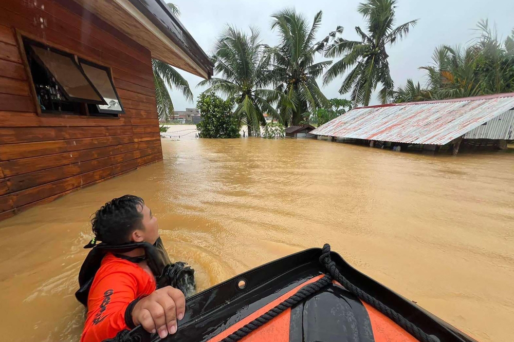 This handout photo taken on November 21, 2023 and received from the Philippine Coast Guard on November 22 shows coast guard personnel wading through floodwaters during evacuation operations at a village in Catarman town, Northern Samar, central Philippines. Photo by Handout / Philippine Coast Guard (PCG) / AFP