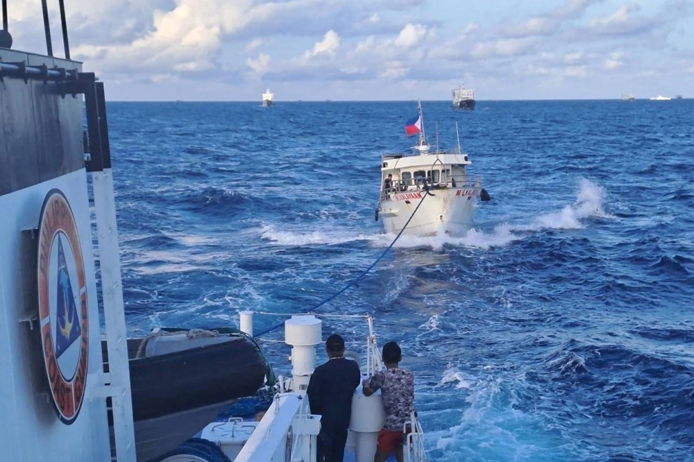 This handout photo taken and released on December 10, 2023 by the Philippine Coast Guard (PCG) shows the M/L Kalayaan chartered supply boat (R) being towed after a Chinese coast guard ship unleashed water cannon onto the vessel, during a mission to deliver provisions at Second Thomas Shoal in disputed waters of the South China Sea. Photo by Handout / Philippine Coast Guard (PCG) / AFP