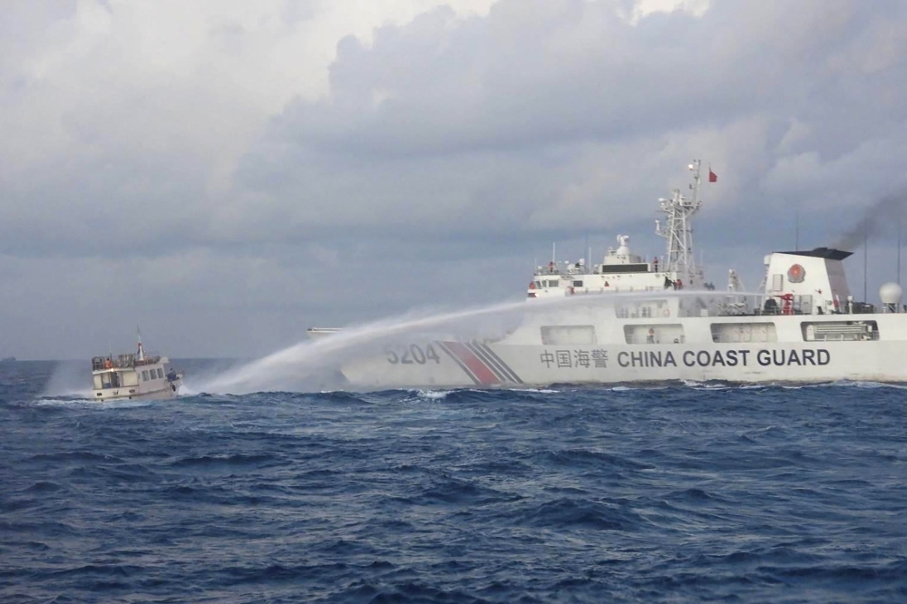 Handout photo taken and released on December 10, 2023 shows a China Coast Guard vessel (R) using water cannon against the M/L Kalayaan chartered supply boat (L) during a mission to deliver provisions at Second Thomas Shoal in disputed waters of the South China Sea. (Photo by Handout / Philippine Coast Guard (PCG) / AFP) 