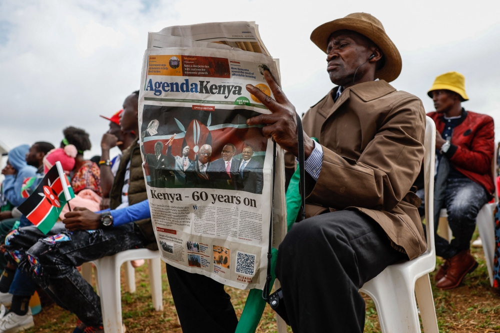 A member of public reads commemorative newspaper as he attends the national celebration marking Kenya's 60th anniversary of independence from Britain, known as Jamhuri Day, in Nairobi on December 12, 2023. (Photo by Simon Maina / AFP)