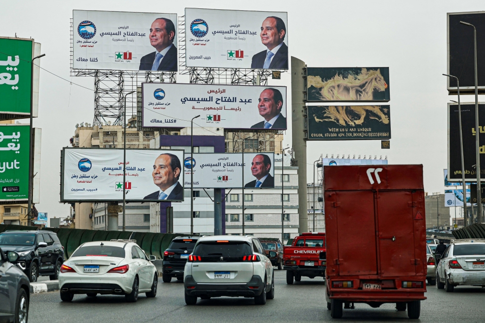 (FILES) Motorists drive past campaign billboards of Egypt's President Abdel Fattah al-Sisi along a street in Cairo on December 7, 2023, ahead of the country's presidential election. (Photo by Khaled DESOUKI / AFP)
