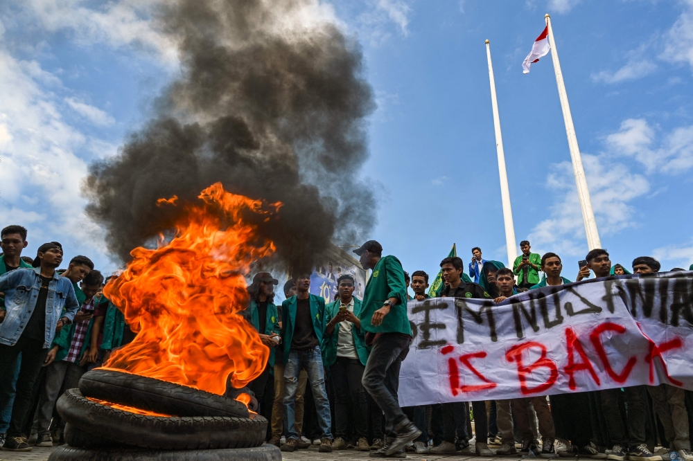 University students burn tyres as they protest against the arrival of Rohingya refugees in front of the People's Representative Council (DPR) in Banda Aceh on December 27, 2023. (Photo by Chaideer Mahyuddin / AFP)