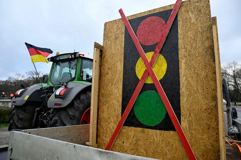 A tractor decorated with a German flag is seen next to a crossed out traffic light sign on January 15, 2024 in Berlin. (Photo by John MacDougall / AFP)