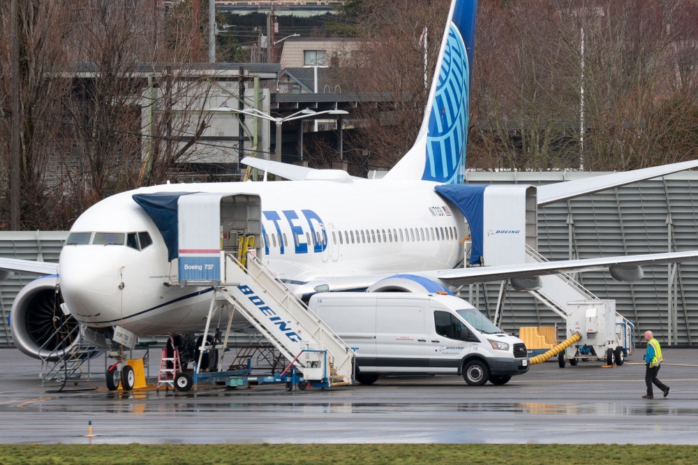 A person walks past a Boeing 737 MAX 8 for United Airlines parked at Renton Municipal Airport adjacent to Boeing's factory in Renton, Washington, on January 25, 2024. Photo by Jason Redmond / AFP