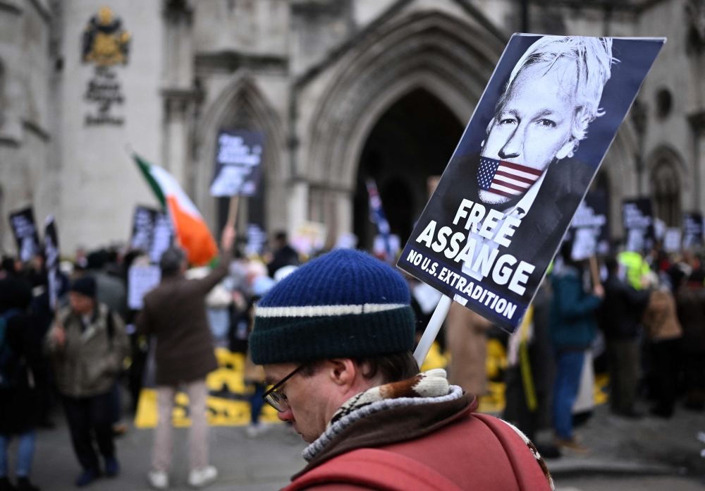 Demonstrators hold placards as they protest outside The Royal Courts of Justice, Britain's High Court, in central London on February 20, 2024, as the high court hears the final UK appeal by WikiLeaks founder Julian Assange against his extradition to the US. (Photo by JUSTIN TALLIS / AFP)
