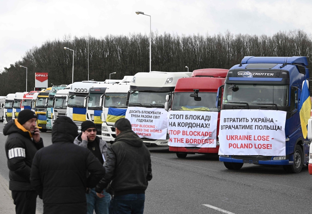 Ukrainian truck drivers take part in a protest against the blockade of the border by the Polish protesters at the Rava-Ruska border crossing point of the Ukrainian-Polish border, with trucks bannered with messages and Ukrainian flags on February 20, 2024, amid the Russian invasion of Ukraine. (Photo by YURIY DYACHYSHYN / AFP)
