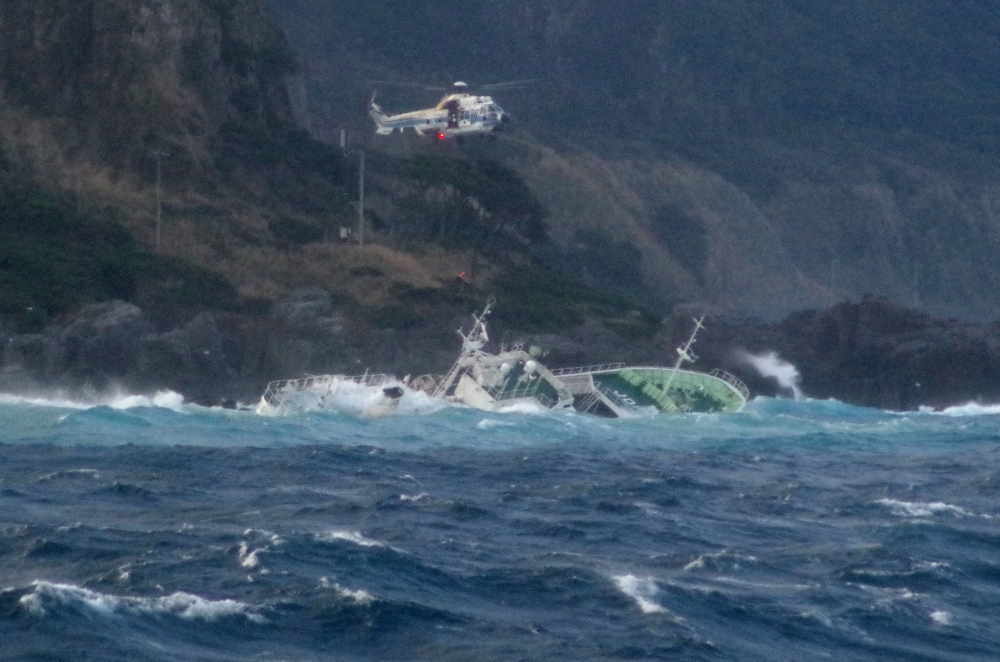This handout photo taken on March 4, 2024 and released by Japan's 3rd Regional Coast Guard Headquarters shows a helicopter conducting a rescue operation after a ship lost power and drifted ashore on Kozushima Island, south of Tokyo. Photo by Handout / Japan's 3rd Regional Coast Guard Headquarters / AFP