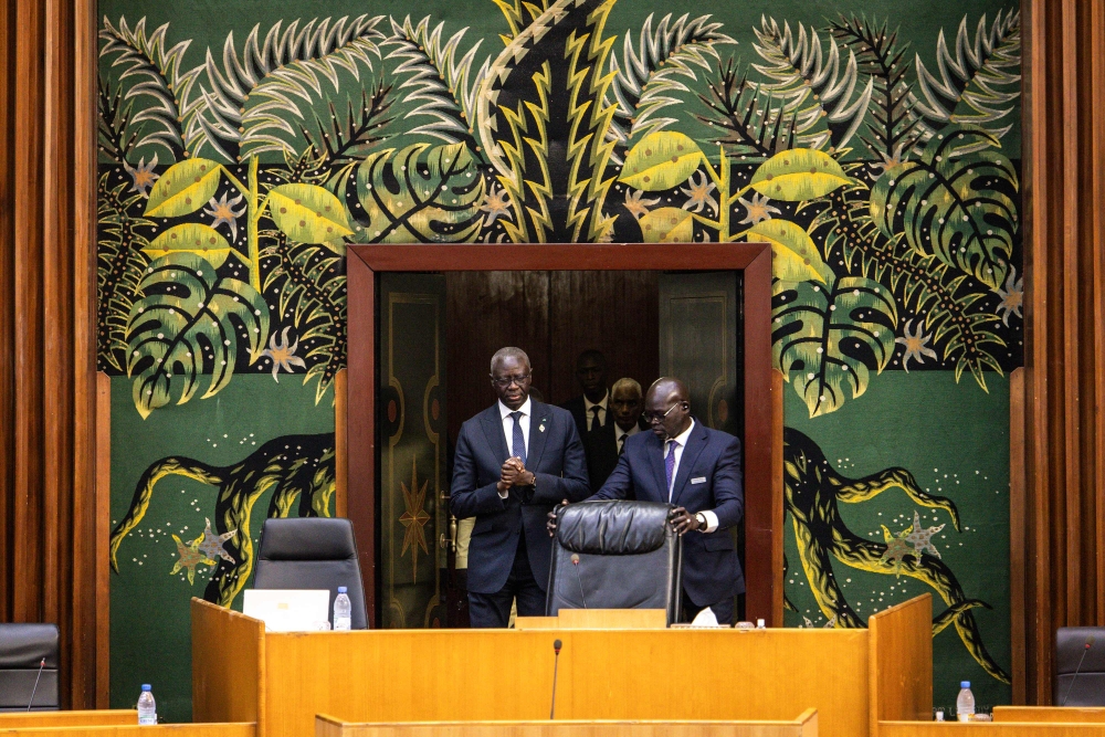 President of the National Assembly, Amadou Mame Diop (L) clasps his hands together as he enters the room at the start of the examination of the proposed amnesty law in Dakar on March 6, 2024. (Photo by JOHN WESSELS / AFP)

