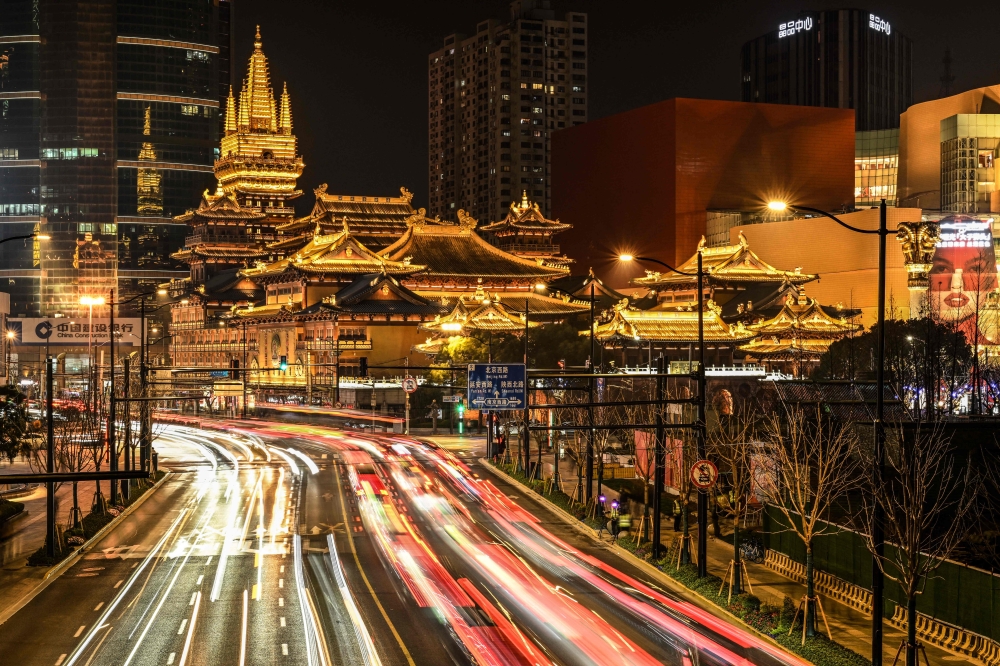 This long exposure picture shows traffic along a road leading to the Jing'an Temple in Shanghai on March 9, 2024. (Photo by Hector RETAMAL / AFP)
