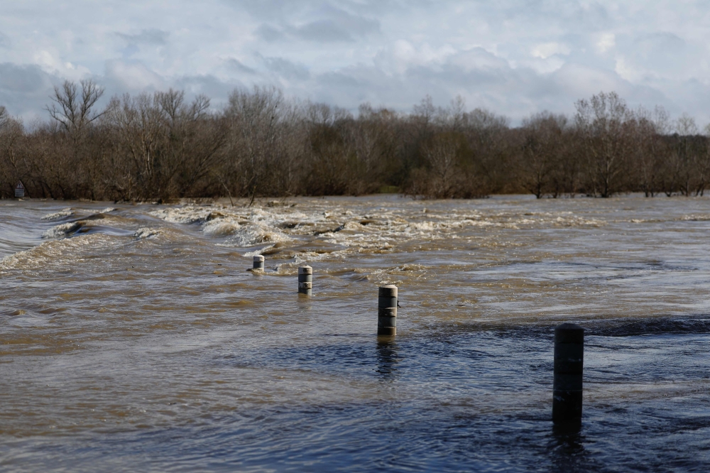 A bridge submerged by the flooded Gard river is pictured in Dions, on March 10, 2024 following heavy rain over south-eastern France. (Photo by Clement Mahoudeau / AFP)
 