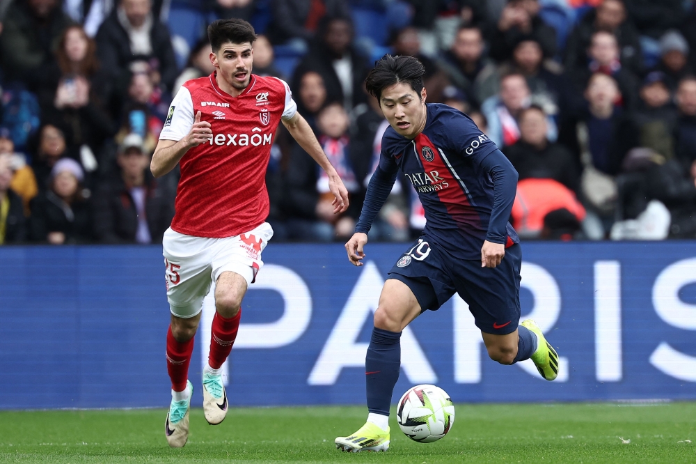 Paris Saint-Germain's South Korean midfielder #19 Lee Kang-in fights for the ball with Reims' Belgian defender #25 Thibault De Smet during the French L1 football match between Paris Saint-Germain (PSG) and Stade de Reims at the Parc des Princes stadium in Paris on March 10, 2024. (Photo by FRANCK FIFE / AFP)
