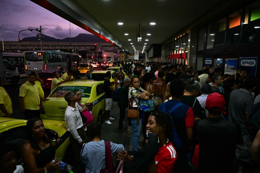 People wait to enter to the Novo Rio bus terminal after the gunman who was holding passengers hostage surrendered in Rio de Janeiro, Brazil on March 12, 2024. (Photo by Pablo PORCIUNCULA / AFP)
