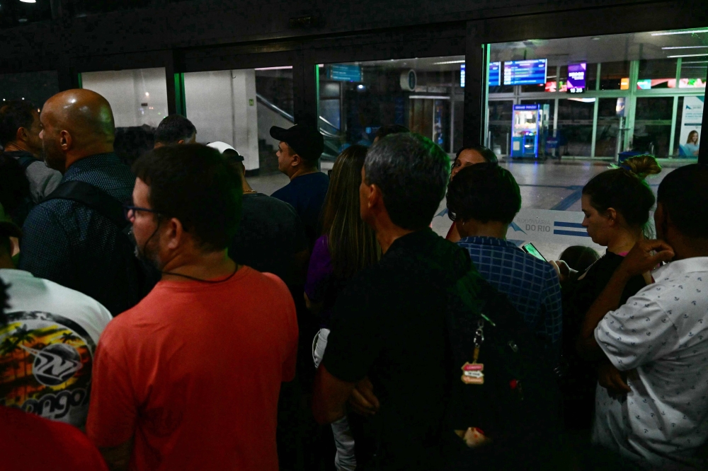 People wait to enter to the Novo Rio bus terminal after the gunman who was holding passengers hostage surrendered in Rio de Janeiro, Brazil on March 12, 2024. (Photo by Pablo PORCIUNCULA / AFP)
