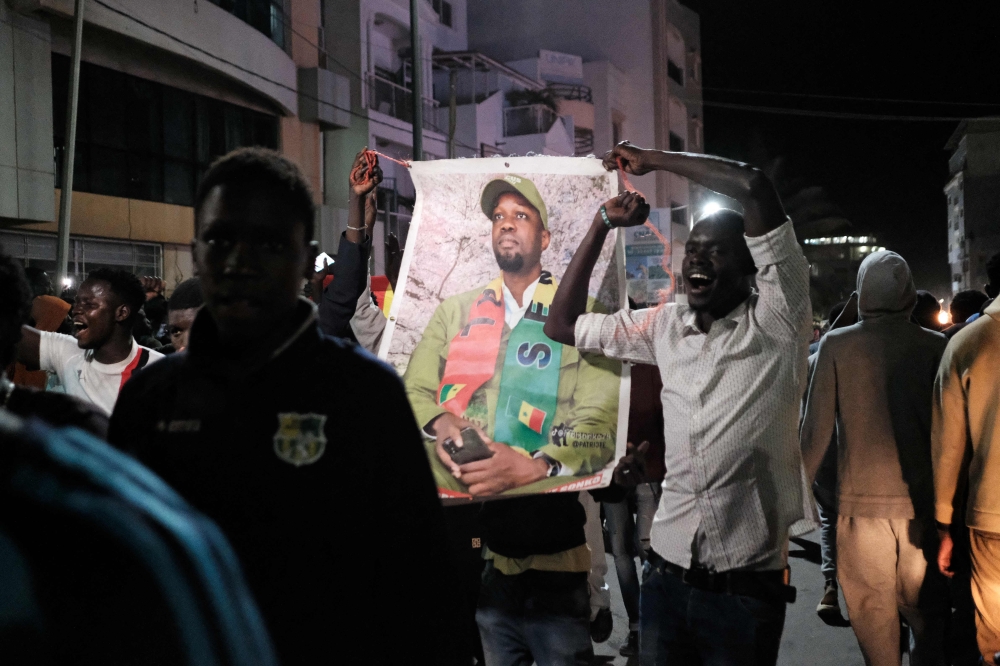 Demonstrators hold a picture of Senegalese opposition leader Ousmane Sonko as they celebrate Sonko's and presidential candidate Bassirou Diomaye Faye's release from prison in Dakar on early March 15, 2024. (Photo by Guy PETERSON / AFP)
