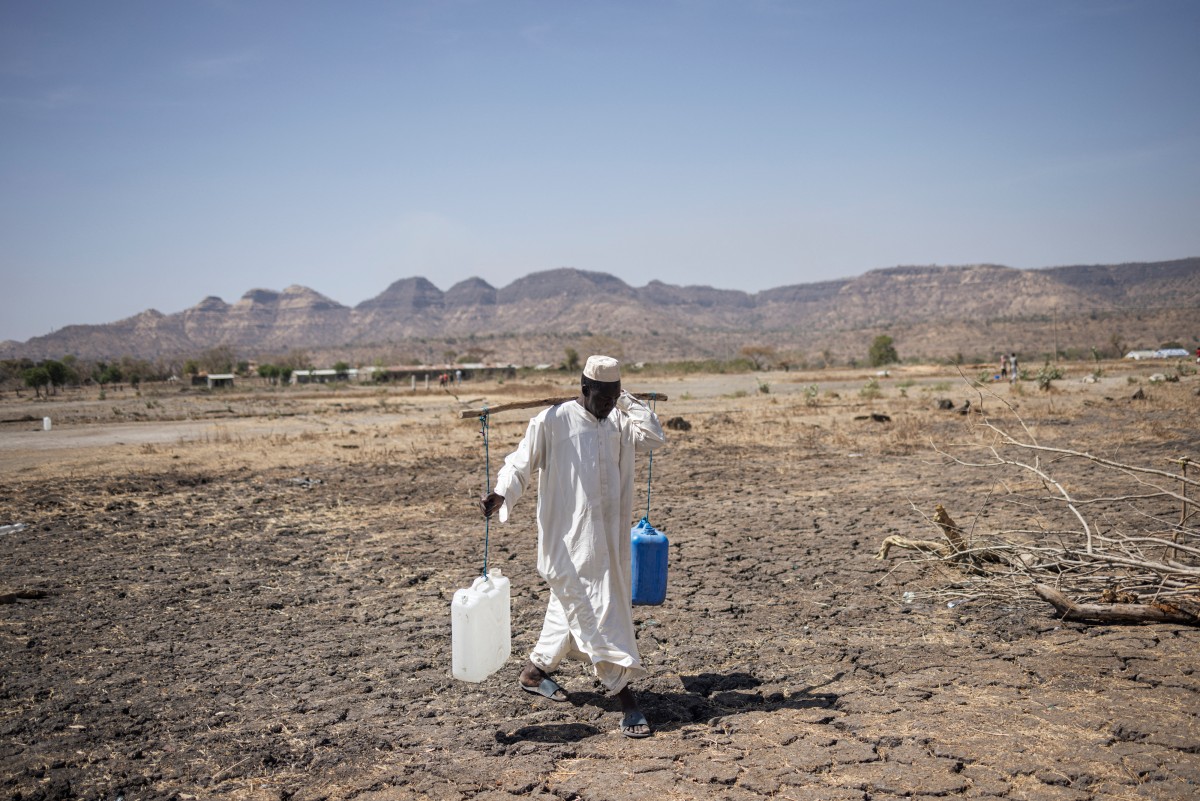 A Sudanese refugee walks back from collecting water in the newly established Awulala refugee camp, near Maganan, 80 km from the Sudanese border in Ethiopia's Amhara region, on February 28, 2024.  (Photo by Michele Spatari / AFP)
