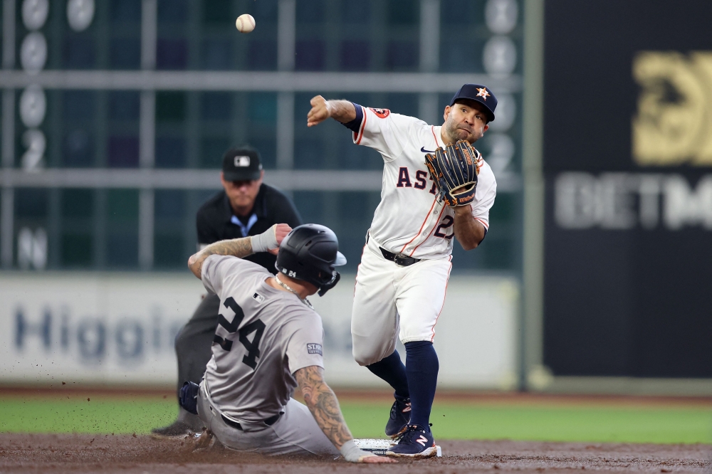 Jose Altuve #27 of the Houston Astros forces out Alex Verdugo #24 of the New York Yankees out at second and throws to first for a double play in the second inning on opening day at Minute Maid Park on March 28, 2024 in Houston, Texas. (Photo by Tim Warner / GETTY IMAGES NORTH AMERICA / Getty Images via AFP)
