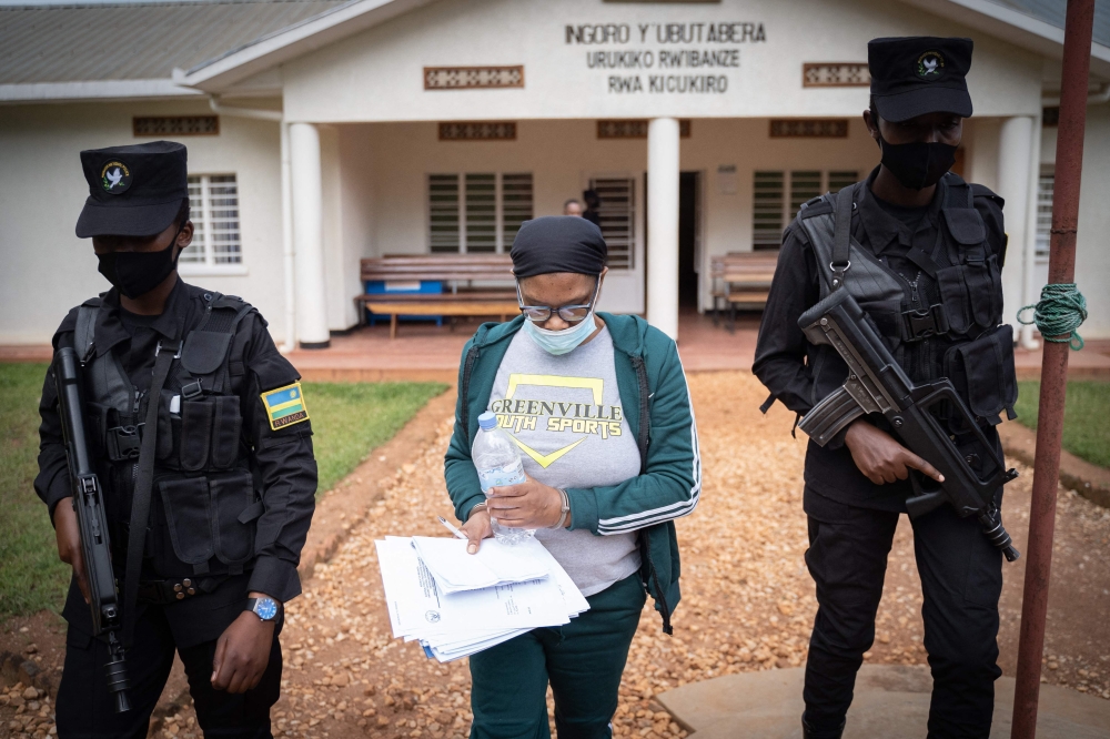 (FILES) Beatrice Munyenyezi (C), 51, who is the first high profile female genocide suspect deported to Rwanda from the US and being charged with seven crimes related to the 1994 Rwandan genocide, is escorted by police officers at the Kicukiro Primary Court in Kigali, Rwanda, on April 28, 2021. (Photo by Simon Wohlfahrt / AFP)
