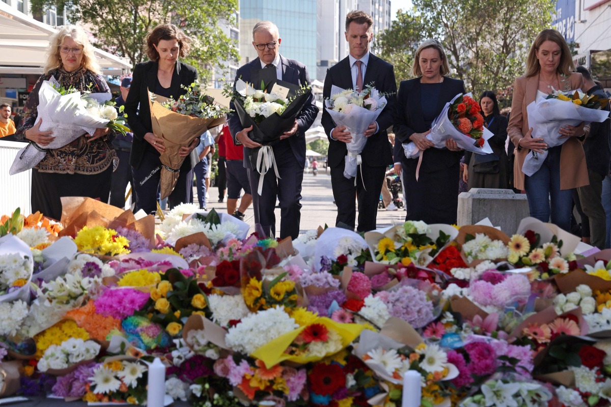 Australian Prime Minister Anthony Albanese (C) stands with New South Wales Premier Chris Minns (4th R) and other officials as they prepare to leave flowers outside the Westfield Bondi Junction shopping mall in sydney on April 14, 2024. (Photo by DAVID GRAY / AFP)

