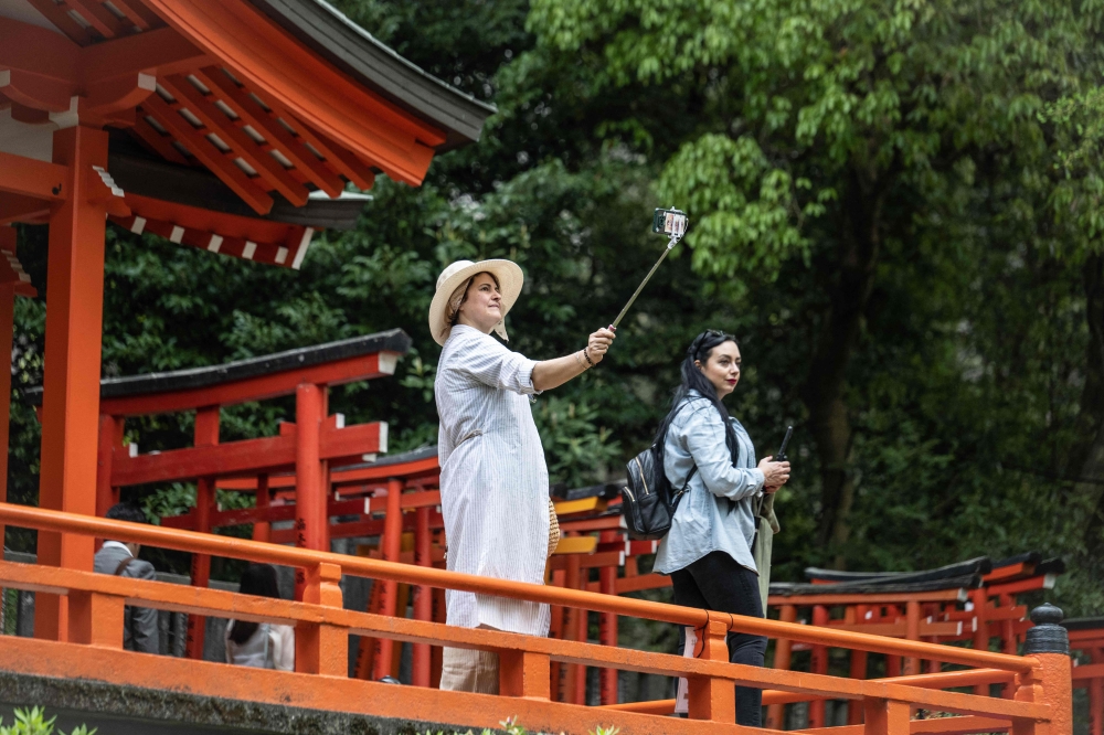 A woman takes photographs at Nezu Shrine in Tokyo on April 17, 2024. (Photo by Yuichi YAMAZAKI / AFP)