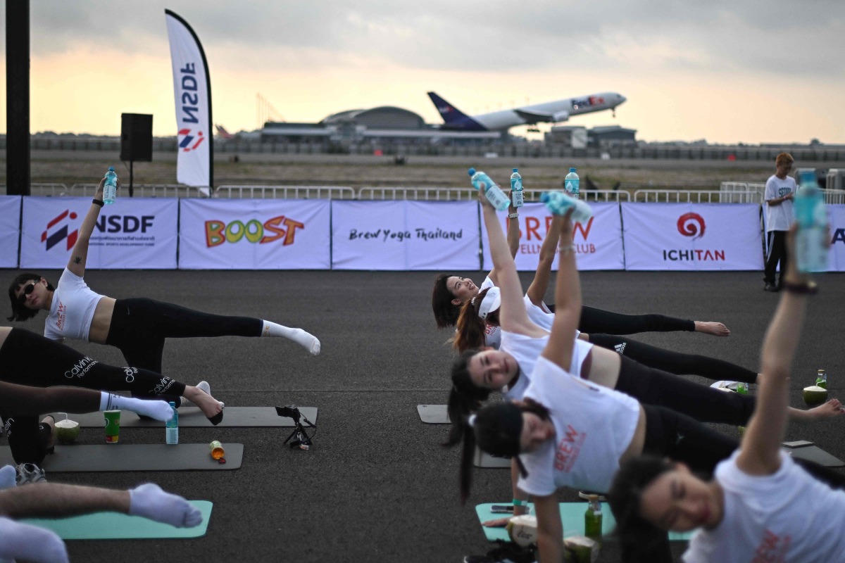 'Feel like a beautiful bird': hundreds do yoga on Thai airport runway