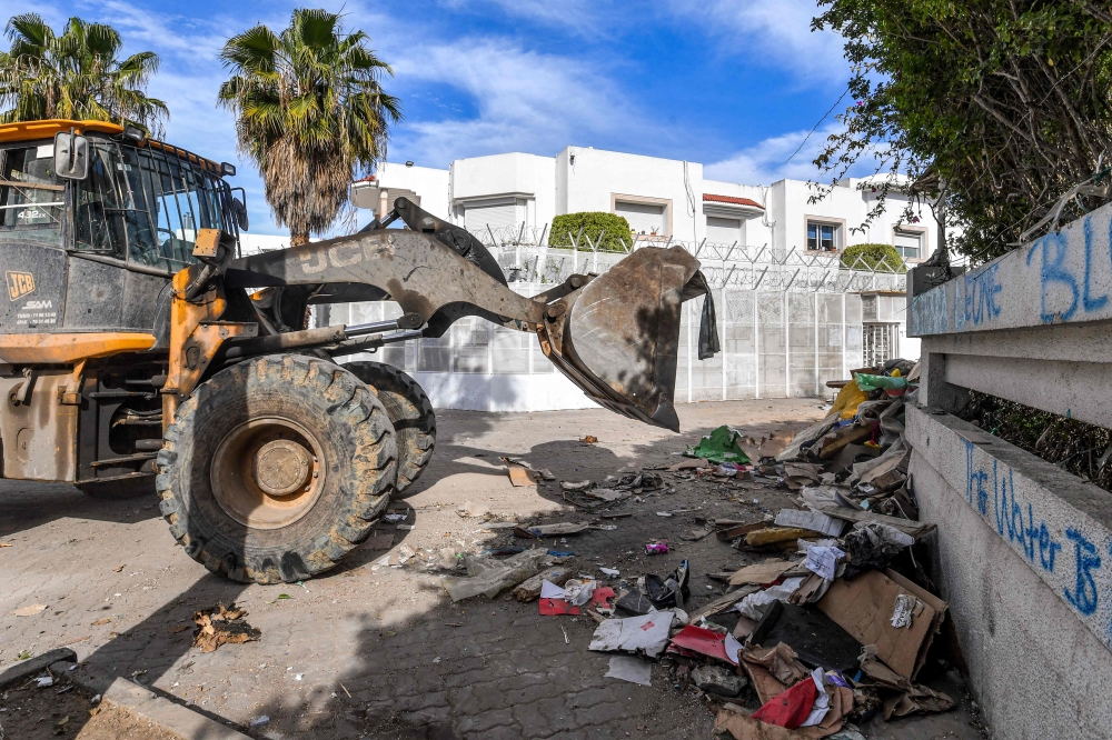 A bulldozer clears debris outside the International Organisation for Migration (IOM) headquarters in Tunis on May 3, 2024 after the local authorities removed an encampment that was erected there by migrants in a forced evacuation. (Photo by FETHI BELAID / AFP)
