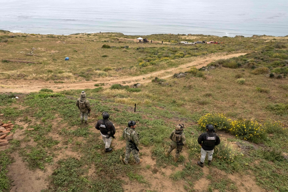 Aerial view showing Mexican marines and National Guard officers standing guard as rescue workers, forensics, and prosecutors work in a waterhole where human remains were found near La Bocana Beach, Santo Tomas delegation in Ensenada, Baja California State, Mexico, on May 3, 2024. (Photo by Guillermo Arias / AFP)

