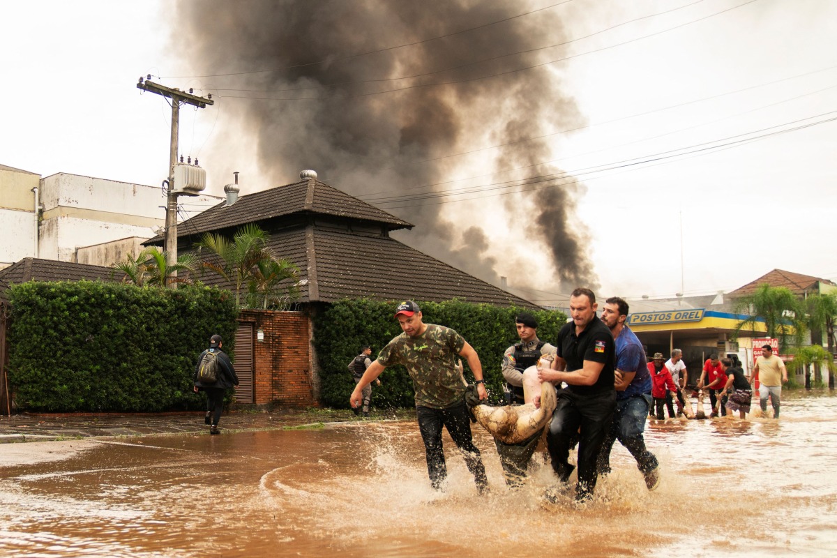 People and policemen carry the body of a victim after an explosion at a petrol station in Porto Alegre, Rio da Grande do State, Brazil on May 4, 2024.