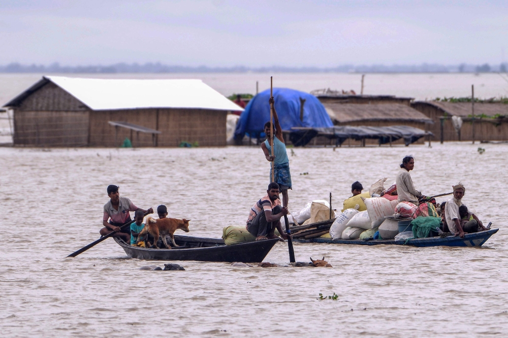 People transport their belongings on boats in a flood affected area at Morigaon district in Assam on July 1, 2024. (Photo by Biju Boro / AFP)