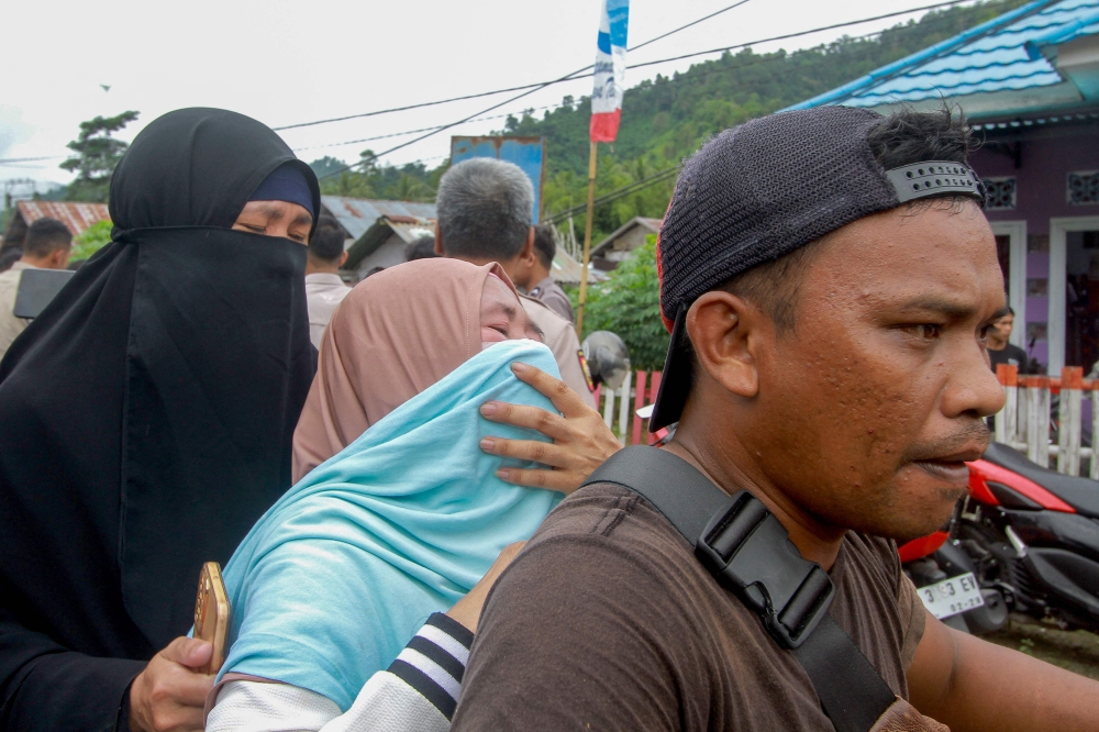 Family members of a victim weep upon finding out about the landslide in Bone Bolango Regency on July 8, 2024. (Photo by Didot / AFP)