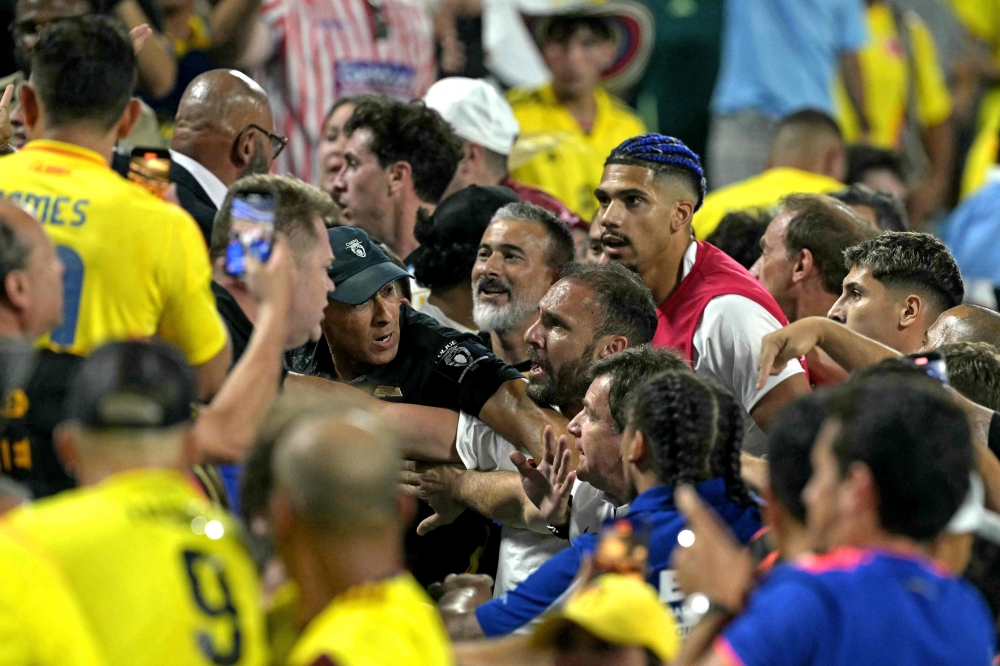 Colombia's supporters (L) clash with Uruguay's supporters, alongside Uruguay's defender #04 Ronald Araujo (R) at Bank of America Stadium, in Charlotte, North Caroline on July 10, 2024. (Photo by Juan Mabromata / AFP)
